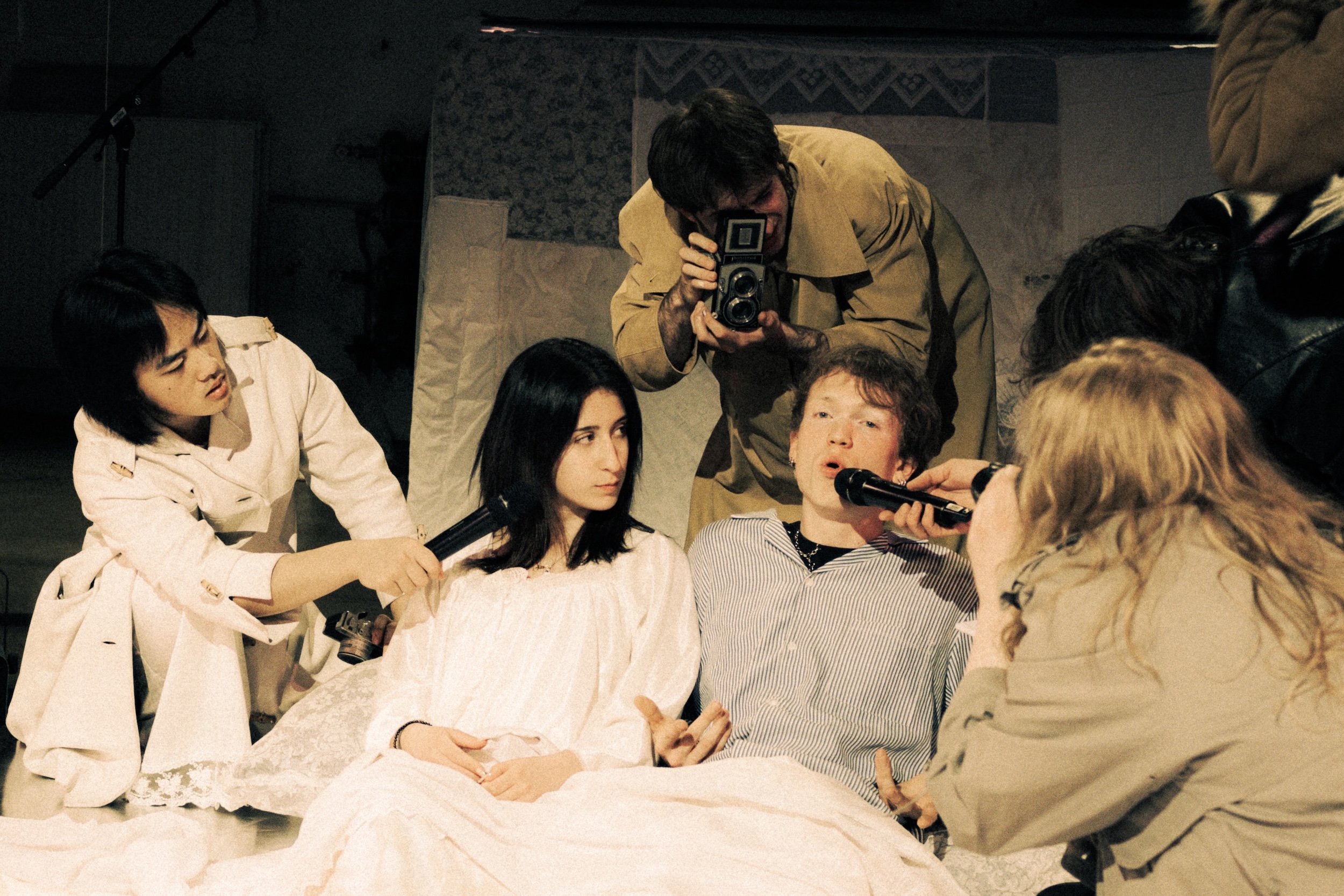 Mehrere Menschen in weißen Kostümen halten zusammen ein großes, mit Spitze verziertes Stofftuch über ihren Köpfen und erzeugen eine Zelt-artige Form