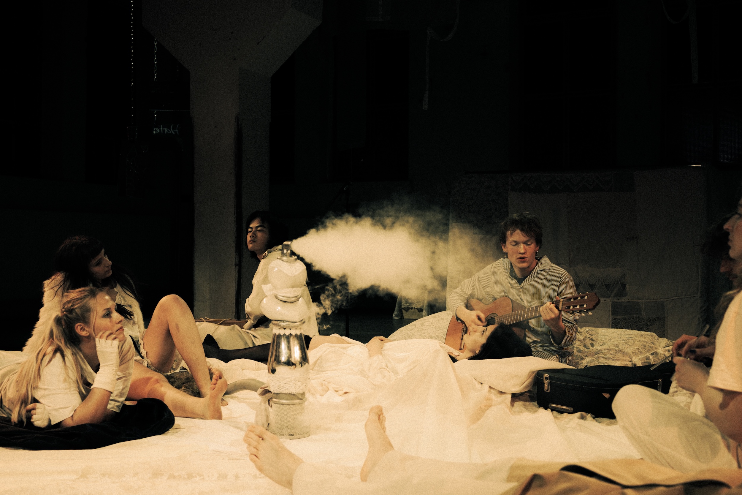 Rund acht Personen umgeben zwei sitzende Menschen und interviewen sie mit Mikrofonen und einer Kamera, alle tragen helle Kostüme